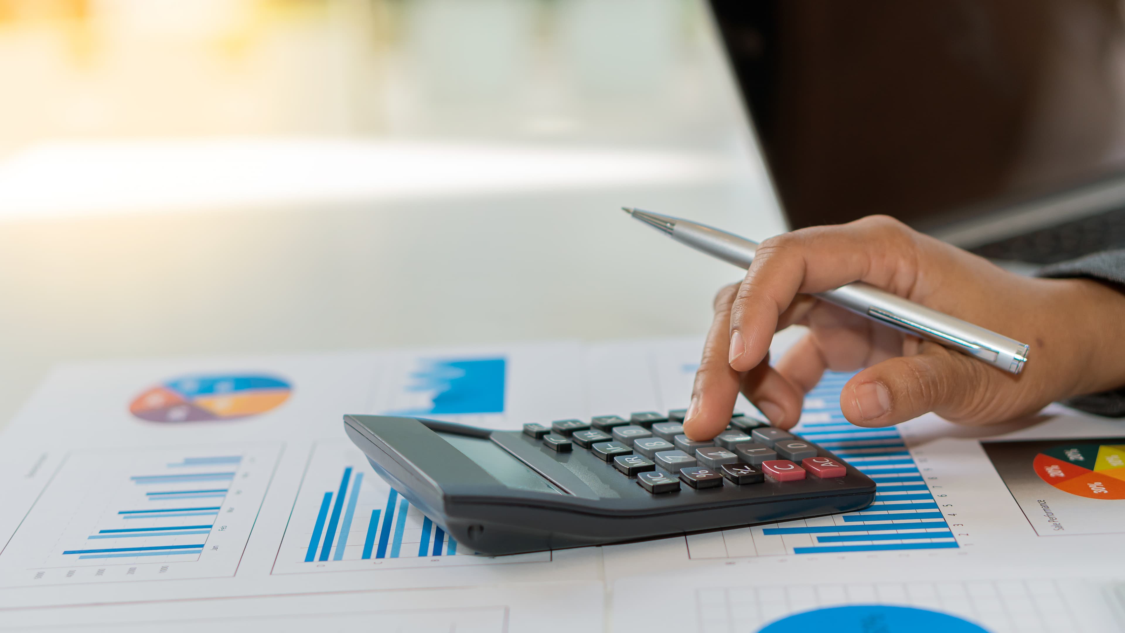 Business people who do business in finance and calculate, analyze, graph the cost of investment. Desk-top tariff system with laptop and calculator with documents